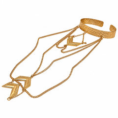 A gold-toned multi-layered jewelry set featuring a textured open cuff bracelet, a long chain necklace with a geometric chevron pendant, and a shorter chain with a matching pendant, displayed on a clean white background.