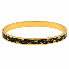 A gold-plated bangle bracelet featuring a black enamel inlay patterned with repeating gold evil eye motifs, shown against a plain white background.