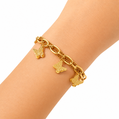 A gold chain bracelet with three textured butterfly charms, shown worn on a person's wrist against a plain white background.