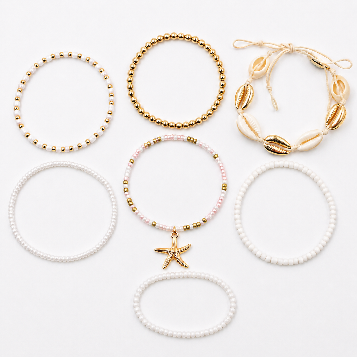 Six beach-themed elastic bracelets arranged on a clean white background. The set includes gold beaded bracelets, a cream and gold shell bracelet, white pearl-like bracelets, a pink beaded bracelet with a gold starfish charm, and a cream cord bracelet with gold shells.