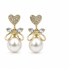 A pair of gold-plated drop earrings featuring a heart-shaped cluster of clear rhinestones, a small bow with marquise-cut clear stones, and a large white pearl dangling below, set against a plain white background.