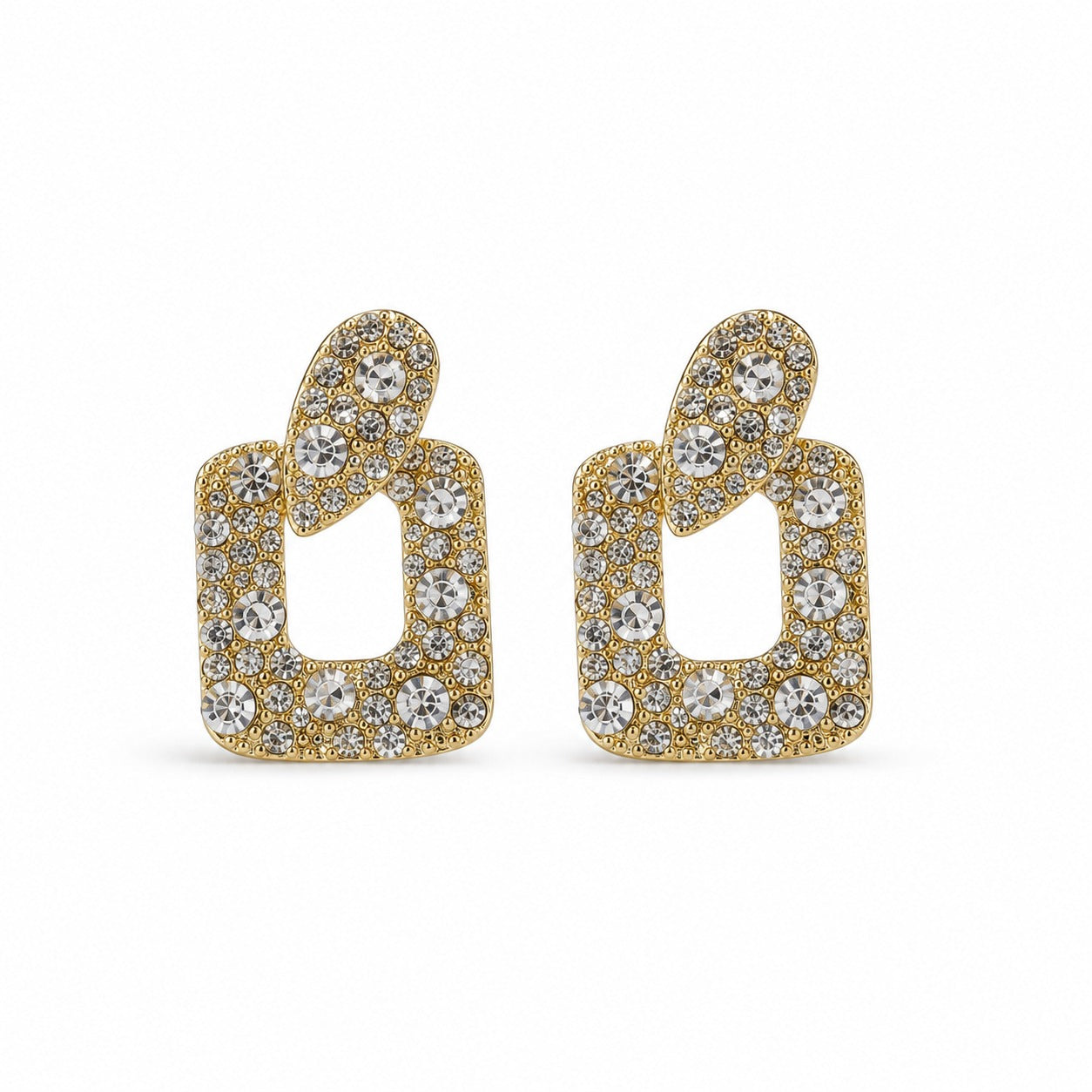 A pair of gold-tone statement earrings featuring a stylized open geometric shape paved with clear round and round-cut crystals, set against a plain white background.