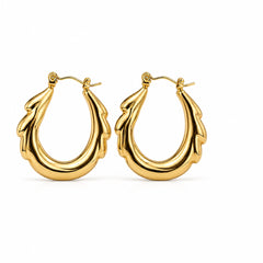 A pair of polished gold hoop earrings with a sculptural, leaf-like or flame-like textured design, displayed on a clean white background.