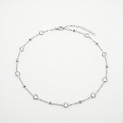 A delicate silver chain anklet featuring seven small, clear round-cut gemstones spaced evenly along the chain, displayed on a clean white background.