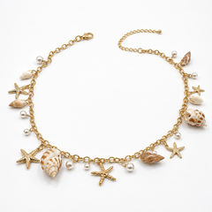 A gold-tone chain necklace featuring dangling seashell and starfish charms, accented with small pearl beads, displayed on a clean white background.
