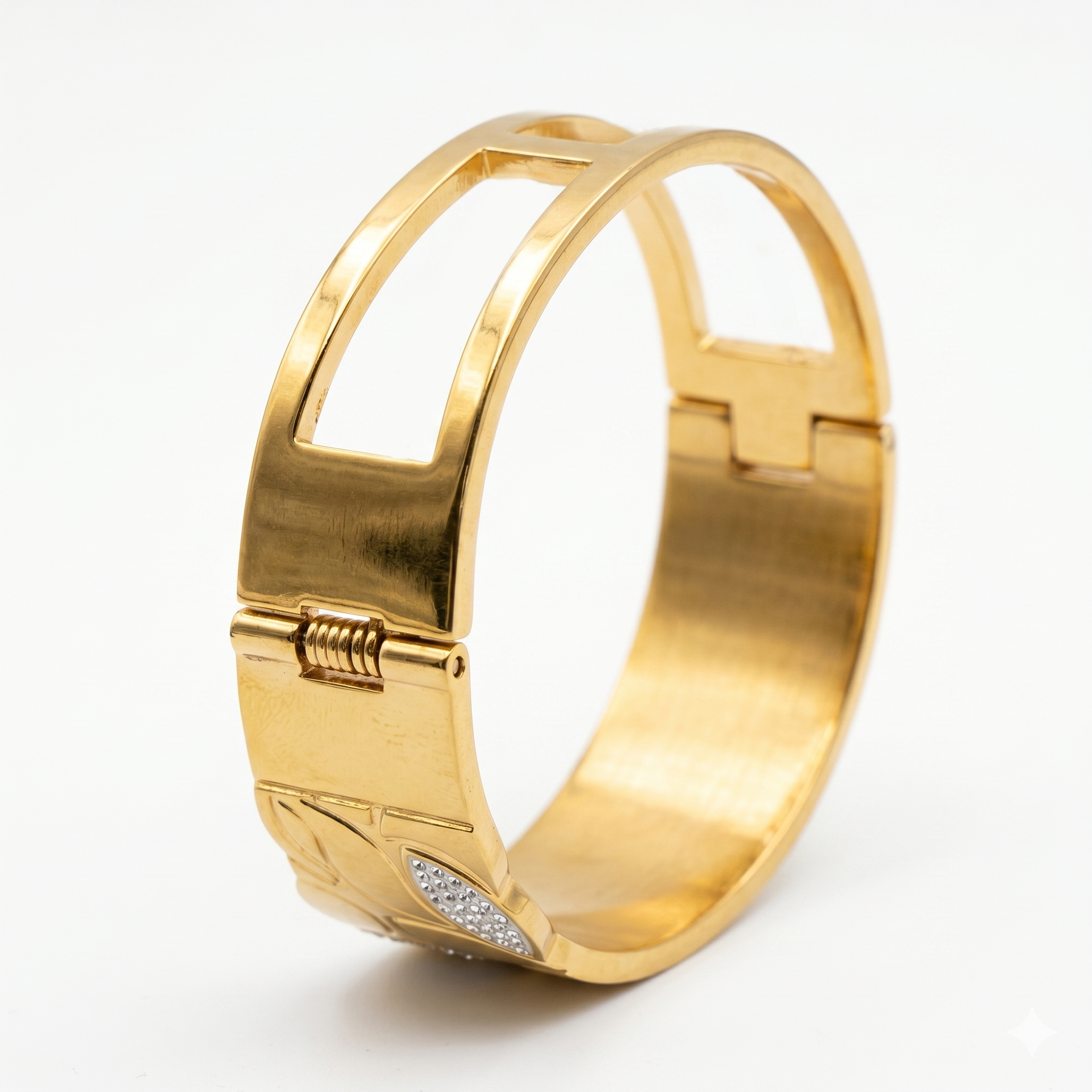 A gold-toned metal cuff bracelet with a hinged clasp and a small pavé-set clear stone accent, shown on a clean white background.
